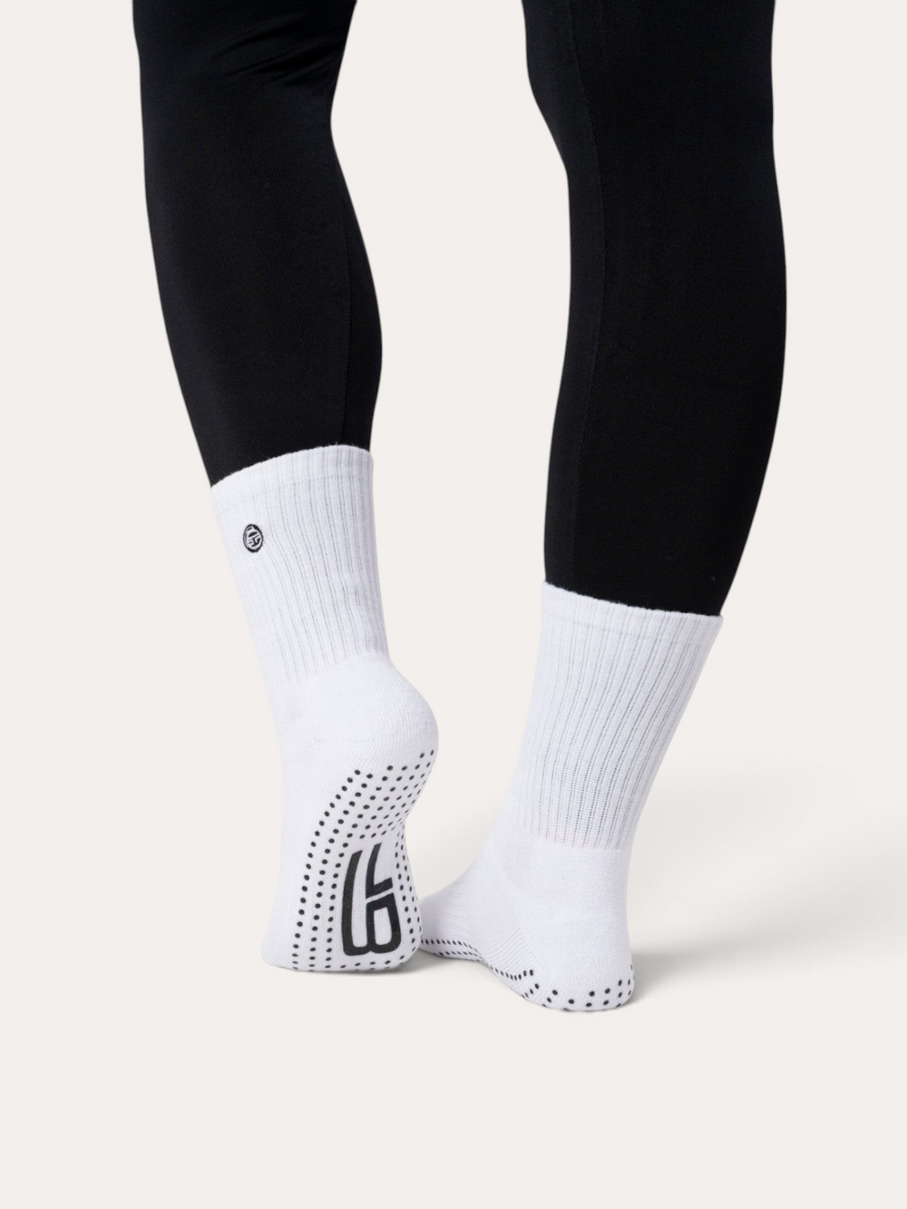 Calzini antiscivolo bianchi Bombafit con suola in silicone per yoga e pilates, indossati con leggings neri
