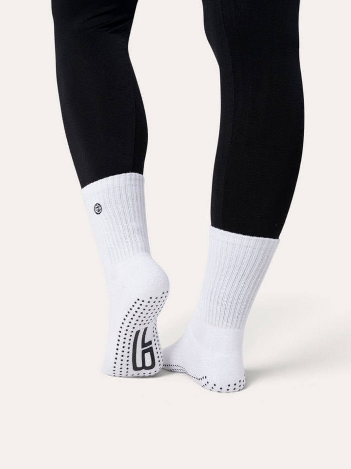 Calzini antiscivolo bianchi Bombafit con suola in silicone per yoga e pilates, indossati con leggings neri
