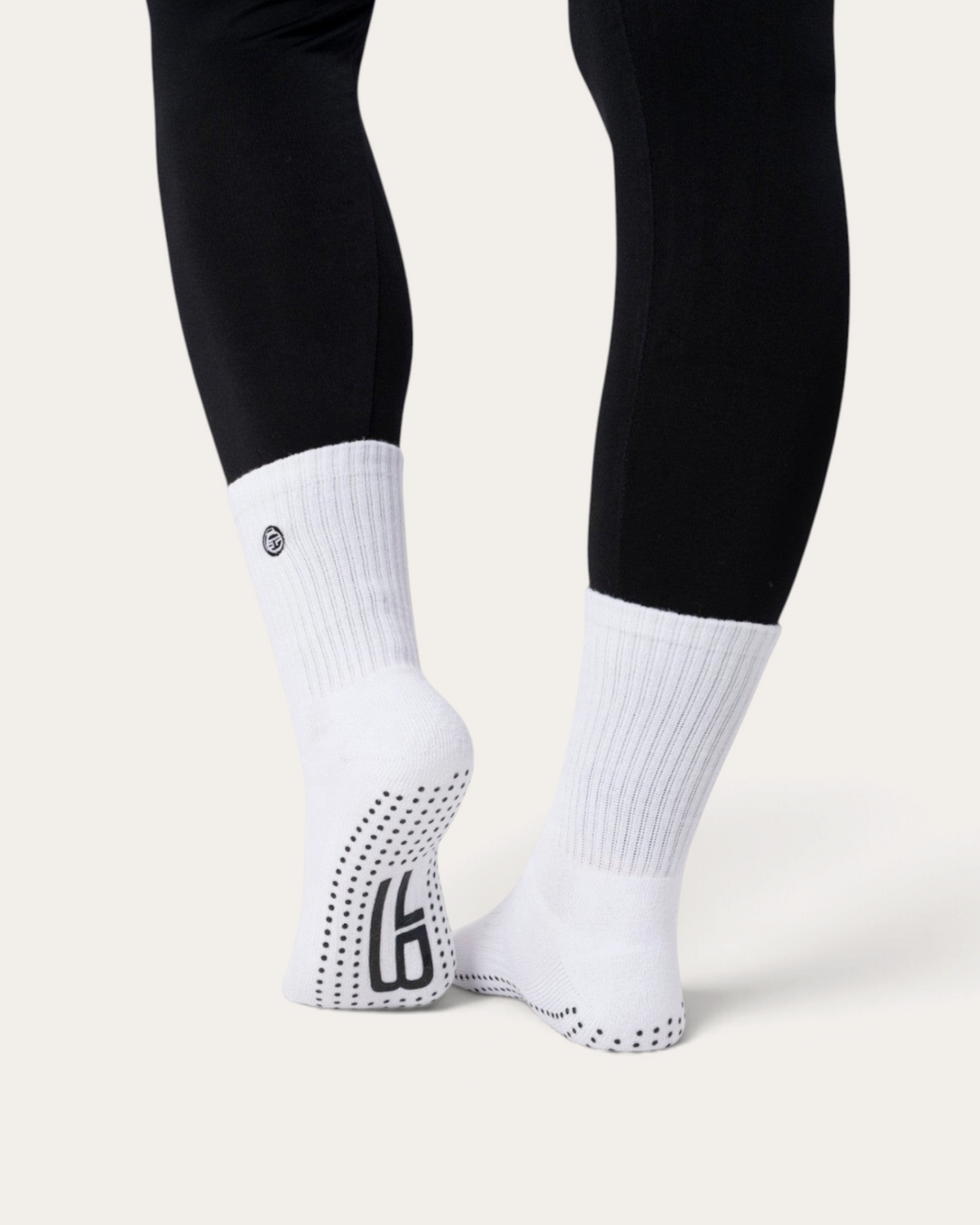 Calzini antiscivolo bianchi Bombafit con suola in silicone per yoga e pilates, indossati con leggings neri
