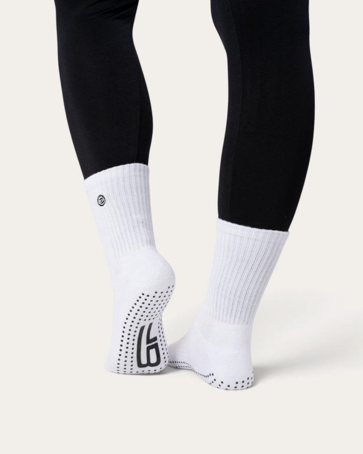 Calzini antiscivolo bianchi Bombafit con suola in silicone per yoga e pilates, indossati con leggings neri