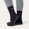 Calzini antiscivolo neri Bombafit con suola grip in silicone per yoga e pilates, indossati con polsino a coste