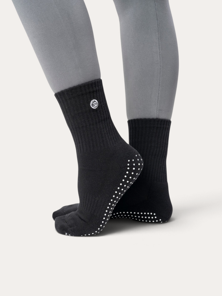 Calzini antiscivolo neri Bombafit con suola grip in silicone per yoga e pilates, indossati con polsino a coste