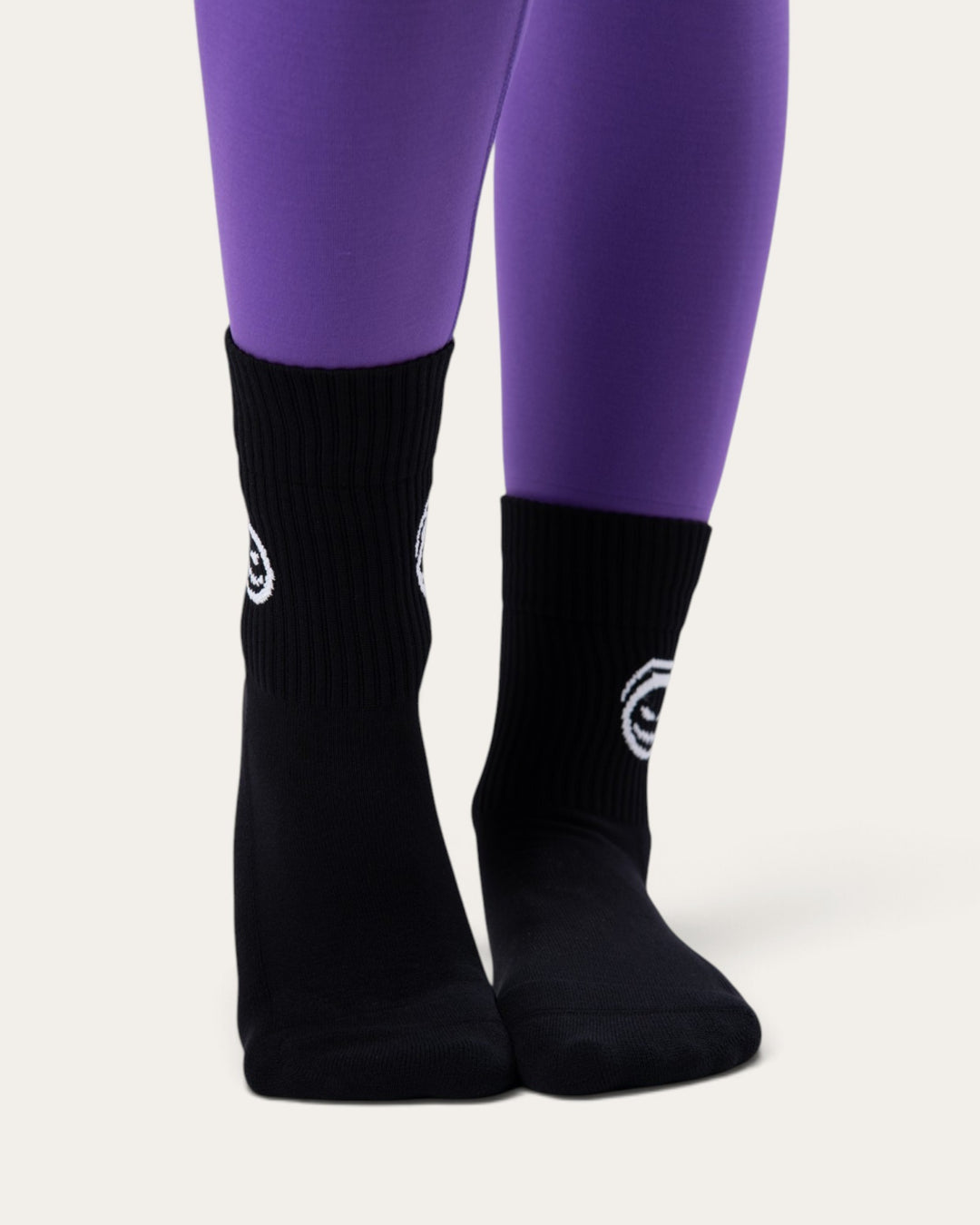 Calzini sportivi neri Bombafit con stampa di zucca bianca, indossati con leggings viola per un look di Halloween