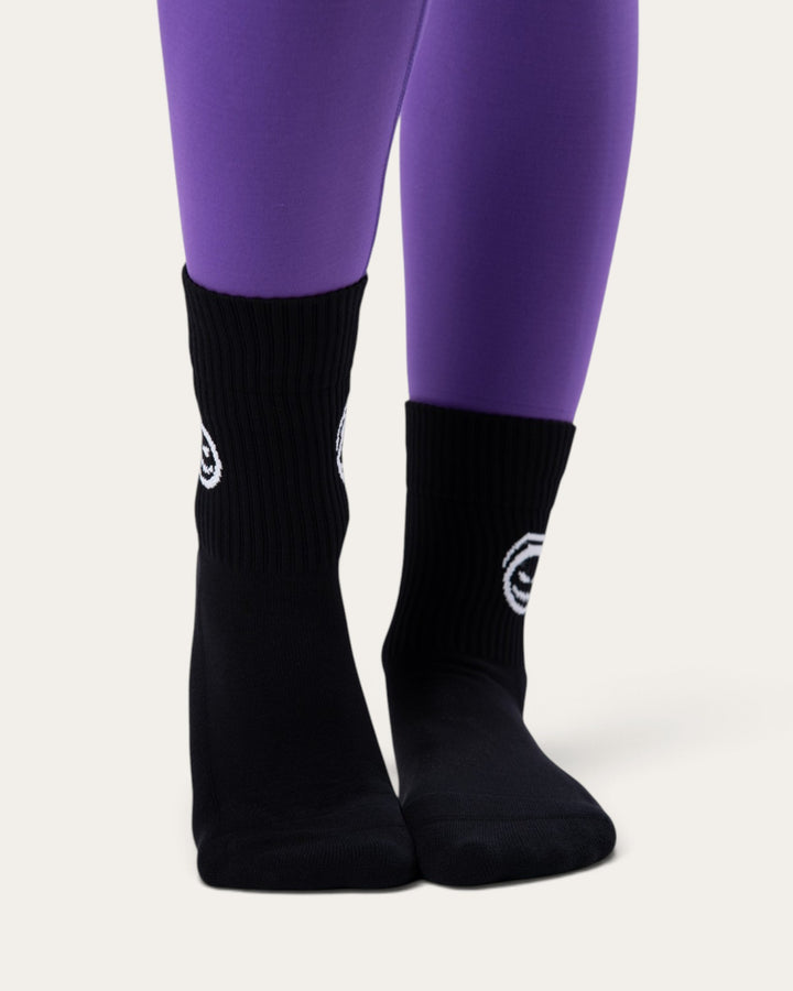Calzini sportivi neri Bombafit con stampa di zucca bianca, indossati con leggings viola per un look di Halloween
