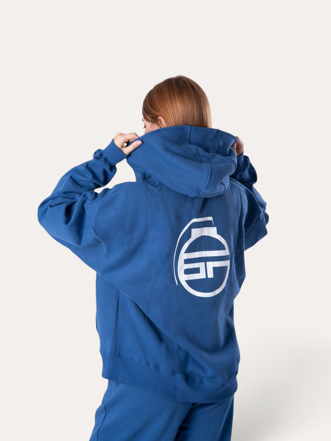Donna che indossa una felpa con cappuccio Bombafit blu reale con logo bianco stampato sul retro