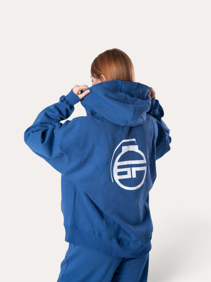 Donna che indossa una felpa con cappuccio Bombafit blu reale con logo bianco stampato sul retro