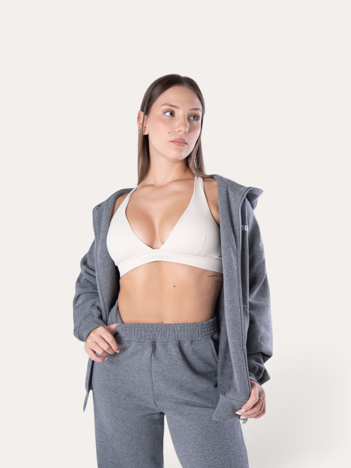 Modella indossa felpa con zip Bombafit Flux color grigio melange sopra un reggiseno sportivo bianco