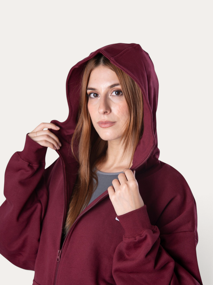 Modella indossa la felpa con cappuccio e zip Bombafit Flux color bordeaux in cotone con vestibilità ampia