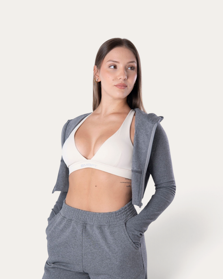 Modella indossa la Bombafit Flux Mini Hoodie grigio melange con zip, abbinata a pantaloni sportivi coordinati