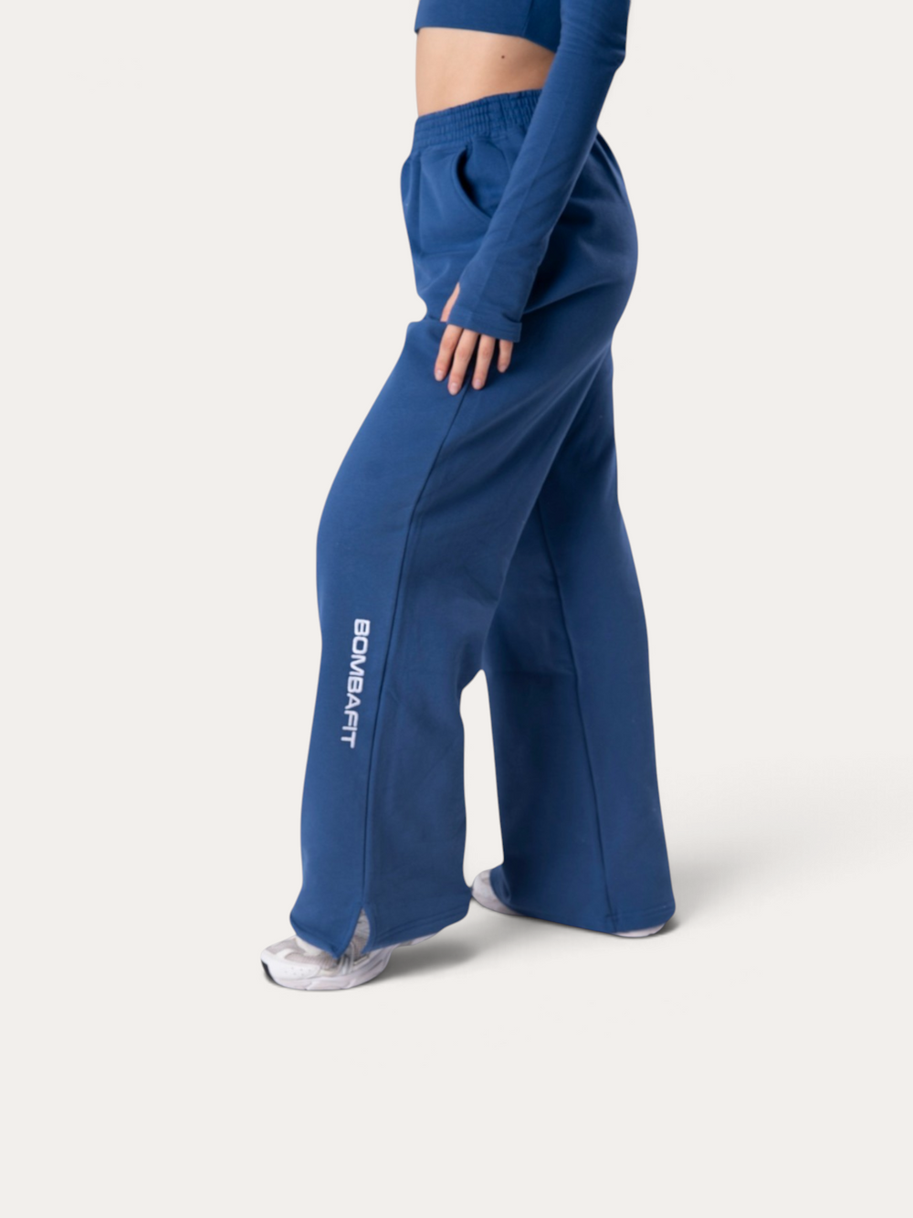 Modella indossa pantaloni della tuta Bombafit Flux blu royal a gamba larga con logo laterale e vita elasticizzata