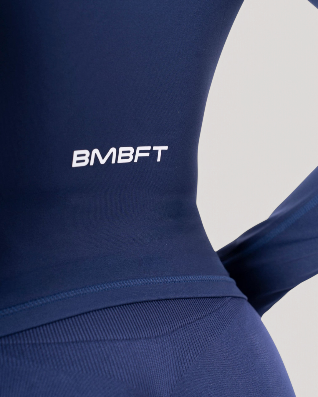 Dettaglio posteriore della giacca a maniche lunghe Bombafit blu notte con logo BMBFT bianco