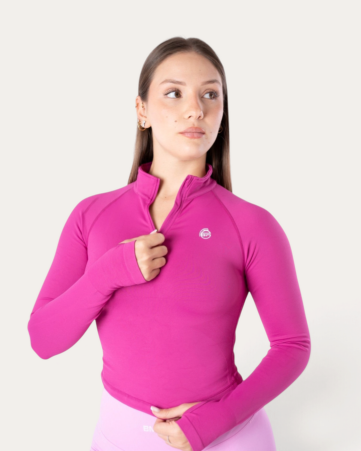 Modella indossa una giacca sportiva a maniche lunghe Bombafit color fucsia con zip frontale e colletto alto