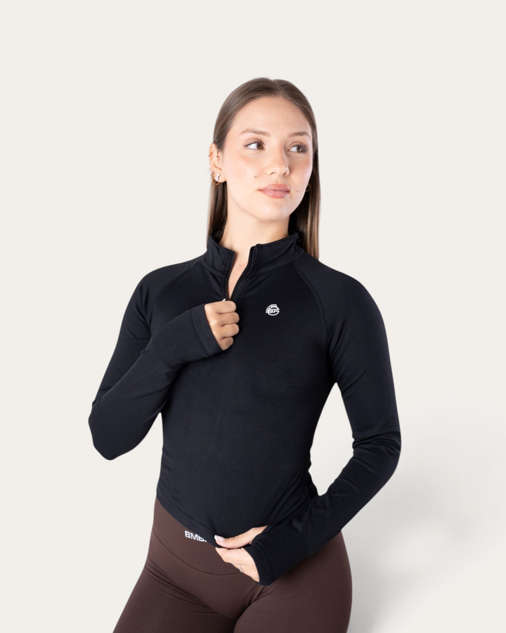 Modella indossa una giacca sportiva nera a maniche lunghe con zip Bombafit, dal taglio aderente e tecnico.