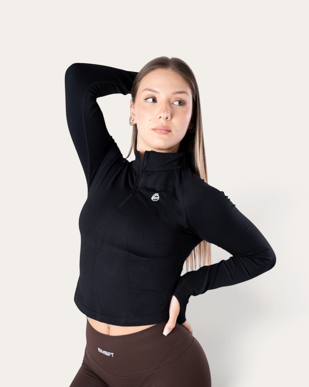 Modella indossa una giacca sportiva a maniche lunghe Bombafit nera con zip corta e logo sul petto