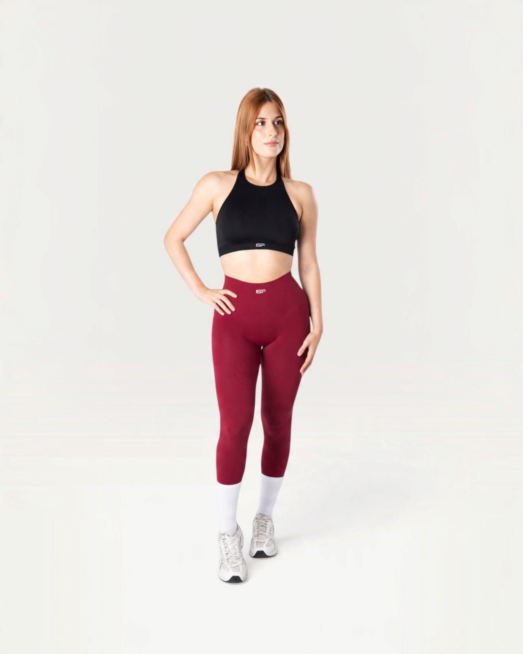 Modella indossa leggings Bombafit Arya Seamless color borgogna a vita alta con effetto push-up e top sportivo nero