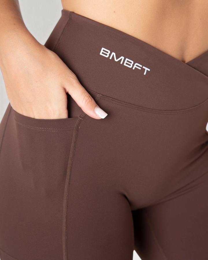 Leggings Bombafit marroni a vita alta con dettaglio incrociato, tasca laterale e logo BMBFT stampato