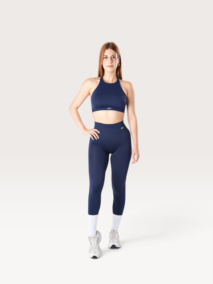 Modella indossa leggings e top sportivo Bombafit Everyday Seamless blu notte con calze bianche e scarpe da ginnastica