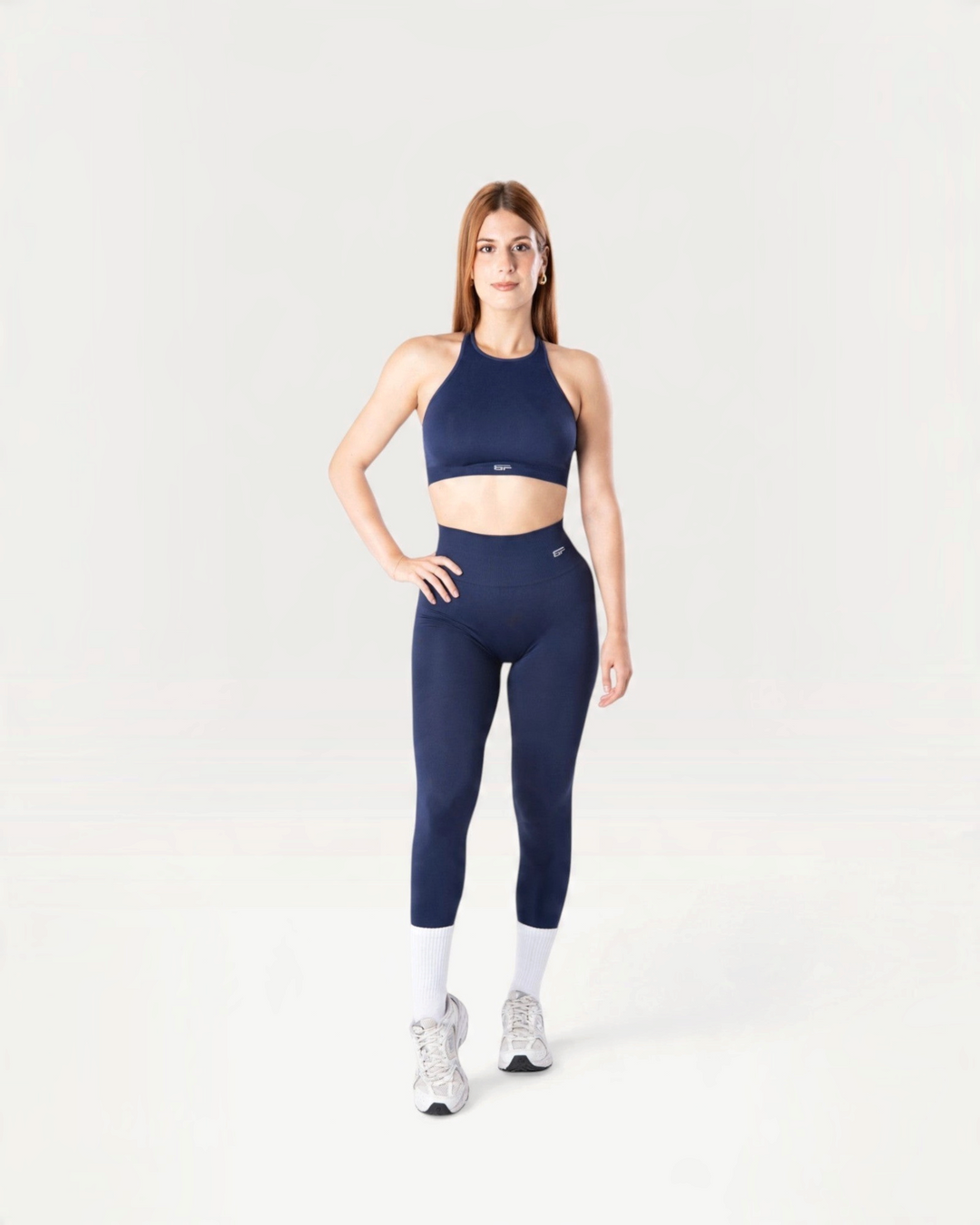 Modella indossa leggings e top sportivo Bombafit Everyday Seamless blu notte con calze bianche e scarpe da ginnastica