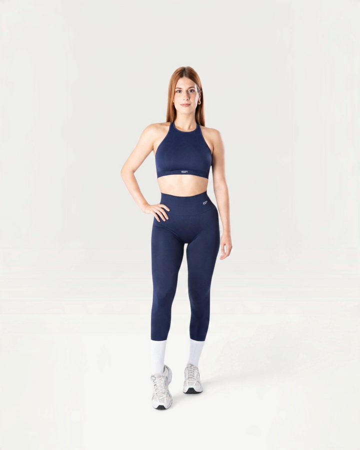 Modella indossa leggings e top sportivo Bombafit Everyday Seamless blu notte con calze bianche e scarpe da ginnastica