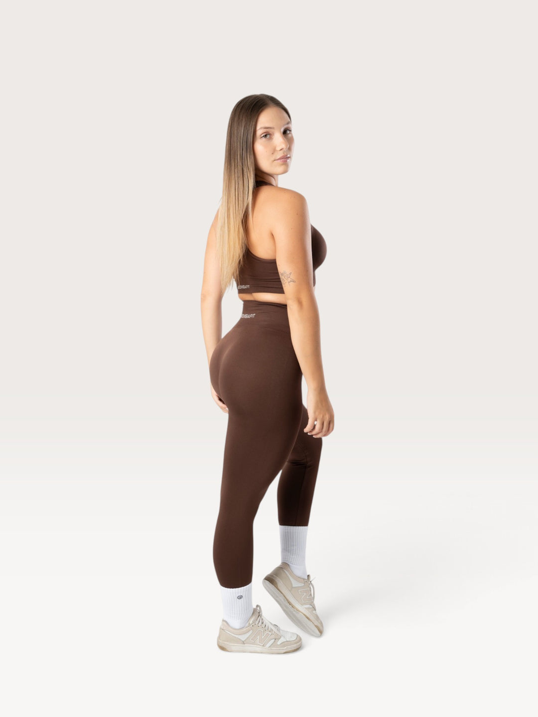 Modella indossa leggings Bombafit marroni a vita alta con effetto push-up e top coordinato in studio