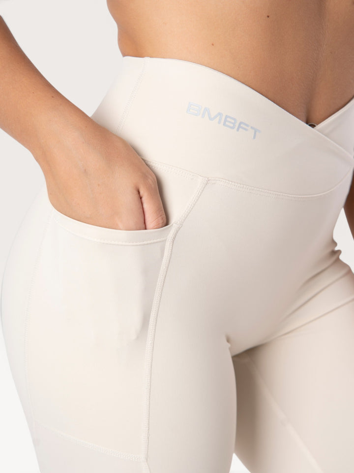 Leggings Bombafit Sense beige a vita alta con dettaglio incrociato, tasca laterale e logo stampato