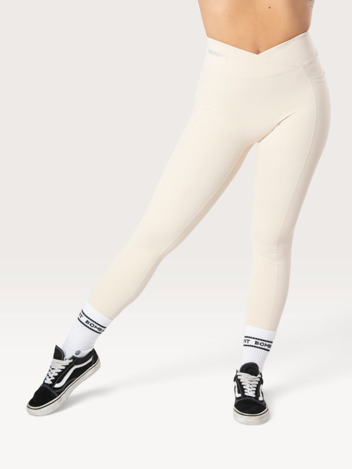 Leggings Bombafit Sense beige a vita alta con incrocio frontale, tasche laterali ed effetto push-up per fitness