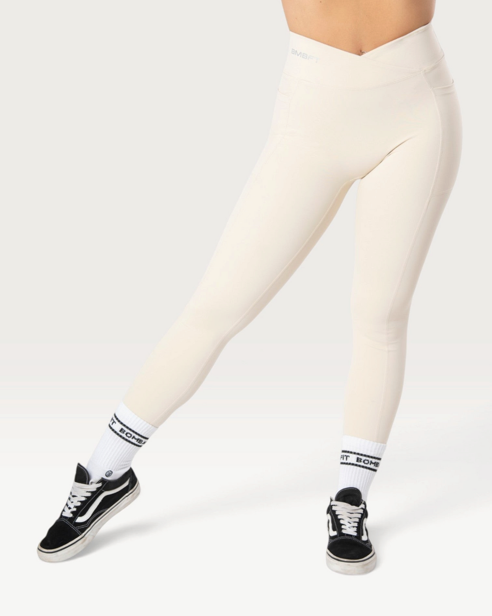 Leggings Bombafit Sense beige a vita alta con incrocio frontale, tasche laterali ed effetto push-up per fitness
