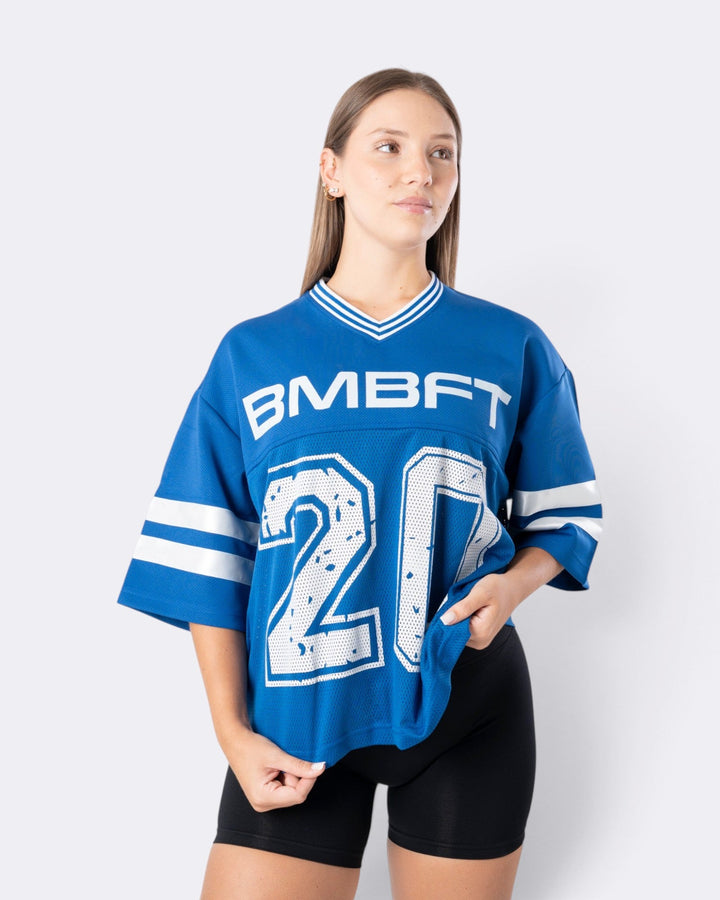 Modella indossa T-shirt oversize Bombafit blu elettrico in stile basket con numero frontale e dettagli a righe