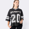 Modella indossa T-shirt oversize nera Bombafit stile basket con numero 20 bianco, scollo a V e dettagli a righe