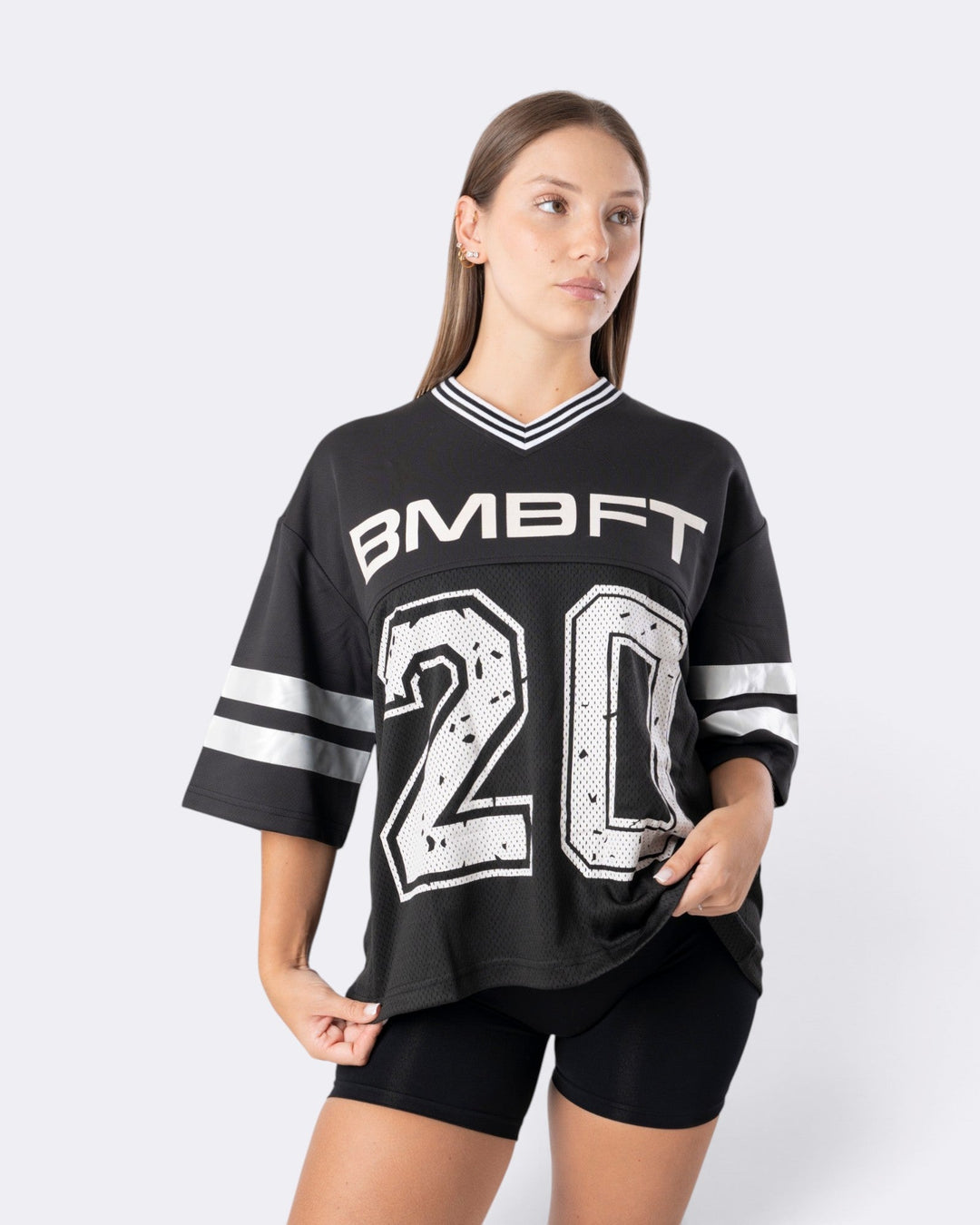 Modella indossa T-shirt oversize nera Bombafit stile basket con numero 20 bianco, scollo a V e dettagli a righe