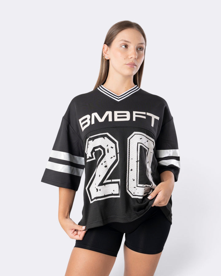 Modella indossa T-shirt oversize nera Bombafit stile basket con numero 20 bianco, scollo a V e dettagli a righe