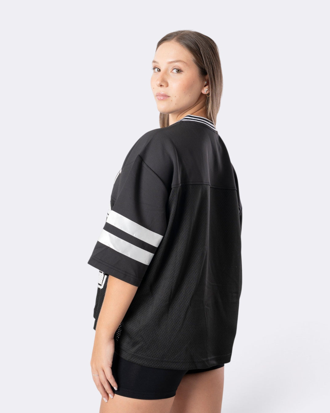 Modella indossa T-shirt oversize nera Bombafit in tessuto tecnico traspirante con bande bianche sulle maniche
