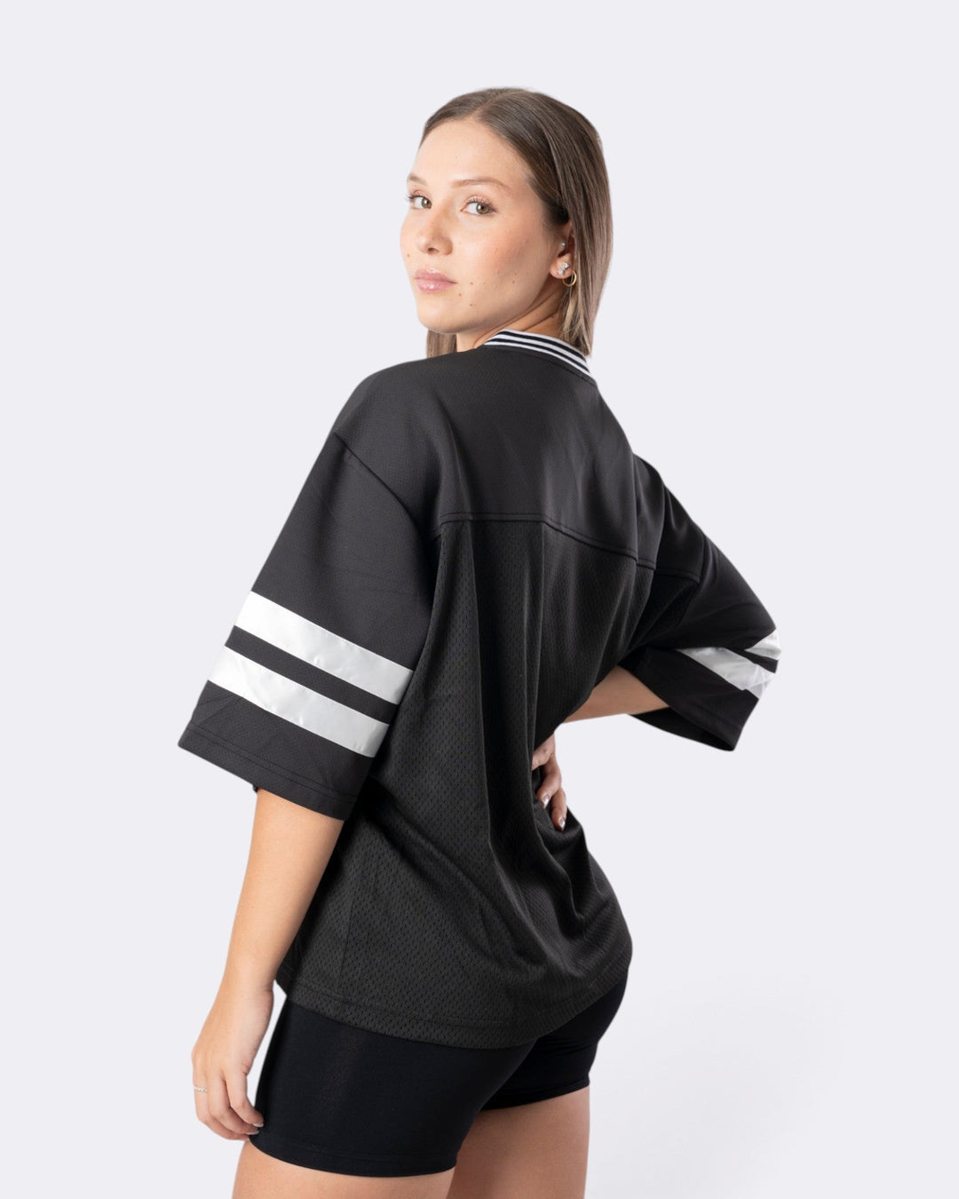 Modella indossa T-shirt oversize nera Bombafit in tessuto tecnico con bande bianche sulle maniche e colletto a costine