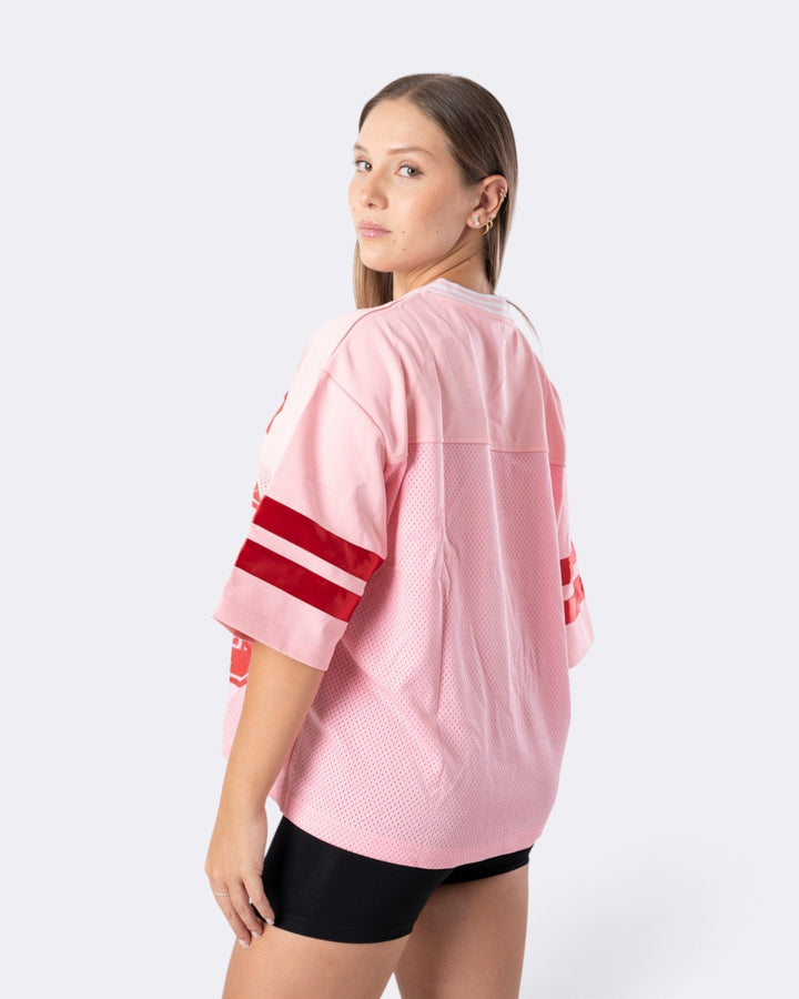 Modella indossa una T-shirt Oversize Number Bombafit rosa in tessuto a rete con bande rosse sulle maniche, vista posteriore