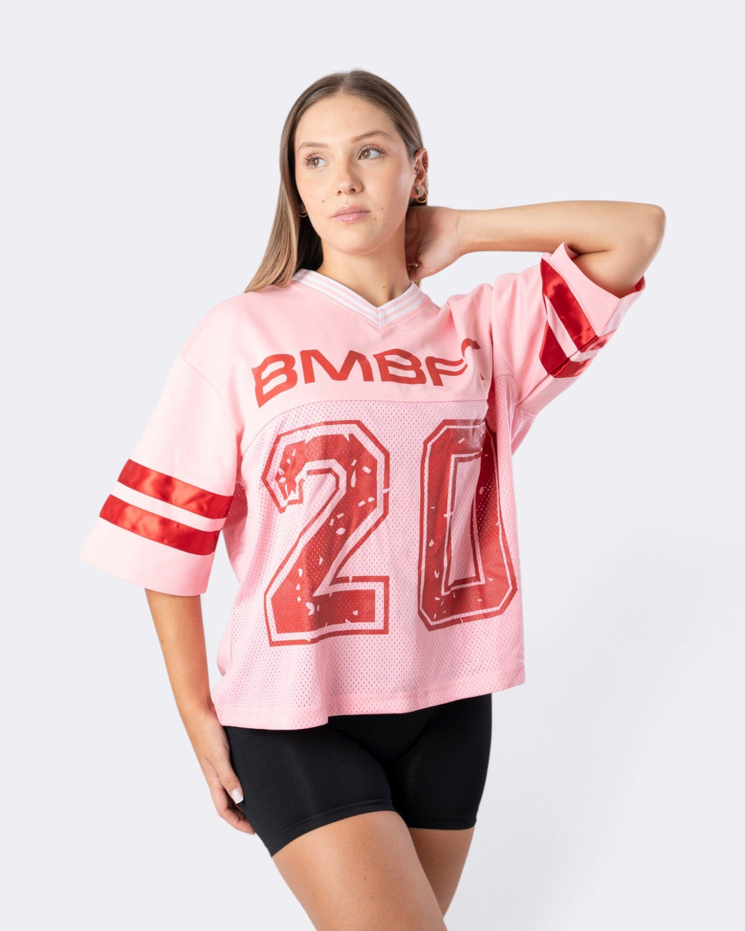 Modella indossa una T-shirt Oversize Number Bombafit rosa in tessuto a rete stile football con numero 20 e scollo a V