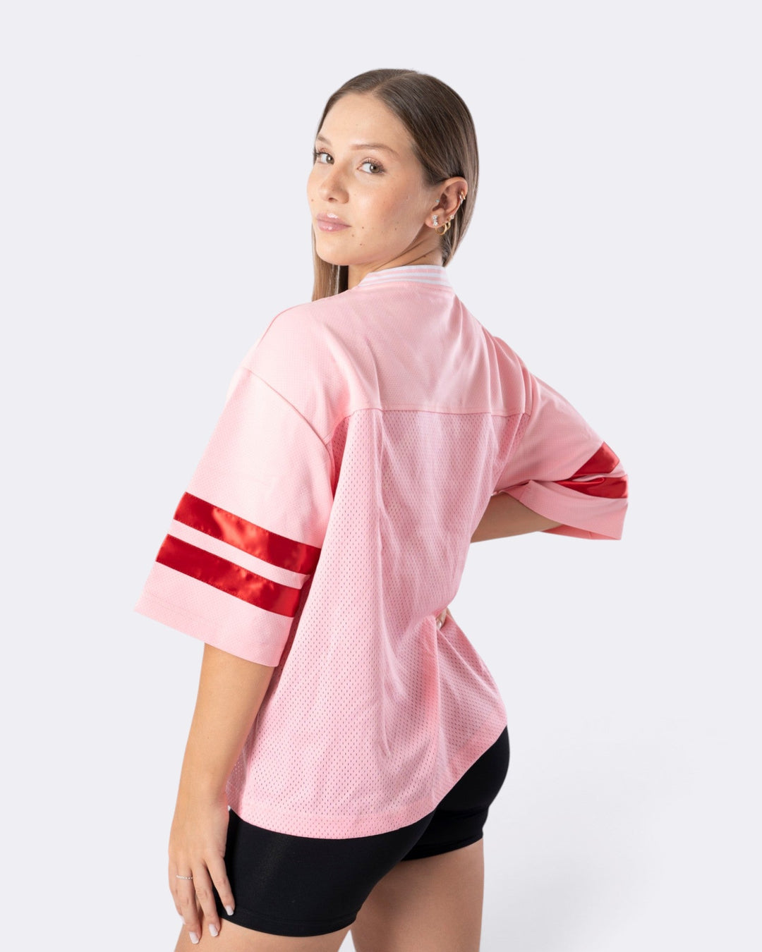 Modella indossa una T-shirt Oversize Number Bombafit rosa in tessuto a rete con bande rosse sulle maniche