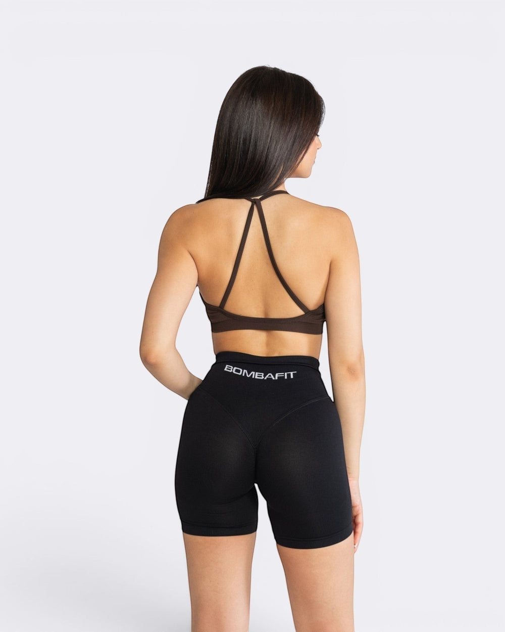 Modella di spalle indossa il top Bombafit Lily Seamless color moka con spalline incrociate e shorts neri