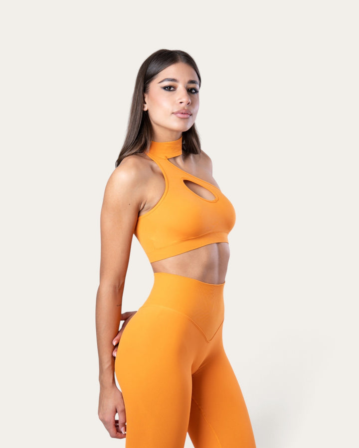 Modella indossa il top sportivo Bombafit Regina delle Zucche arancione senza cuciture con scollo choker e cut-out