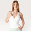 Modella indossa il top sportivo Bombafit Sense Halter bianco con scollo all'americana e design incrociato sul davanti
