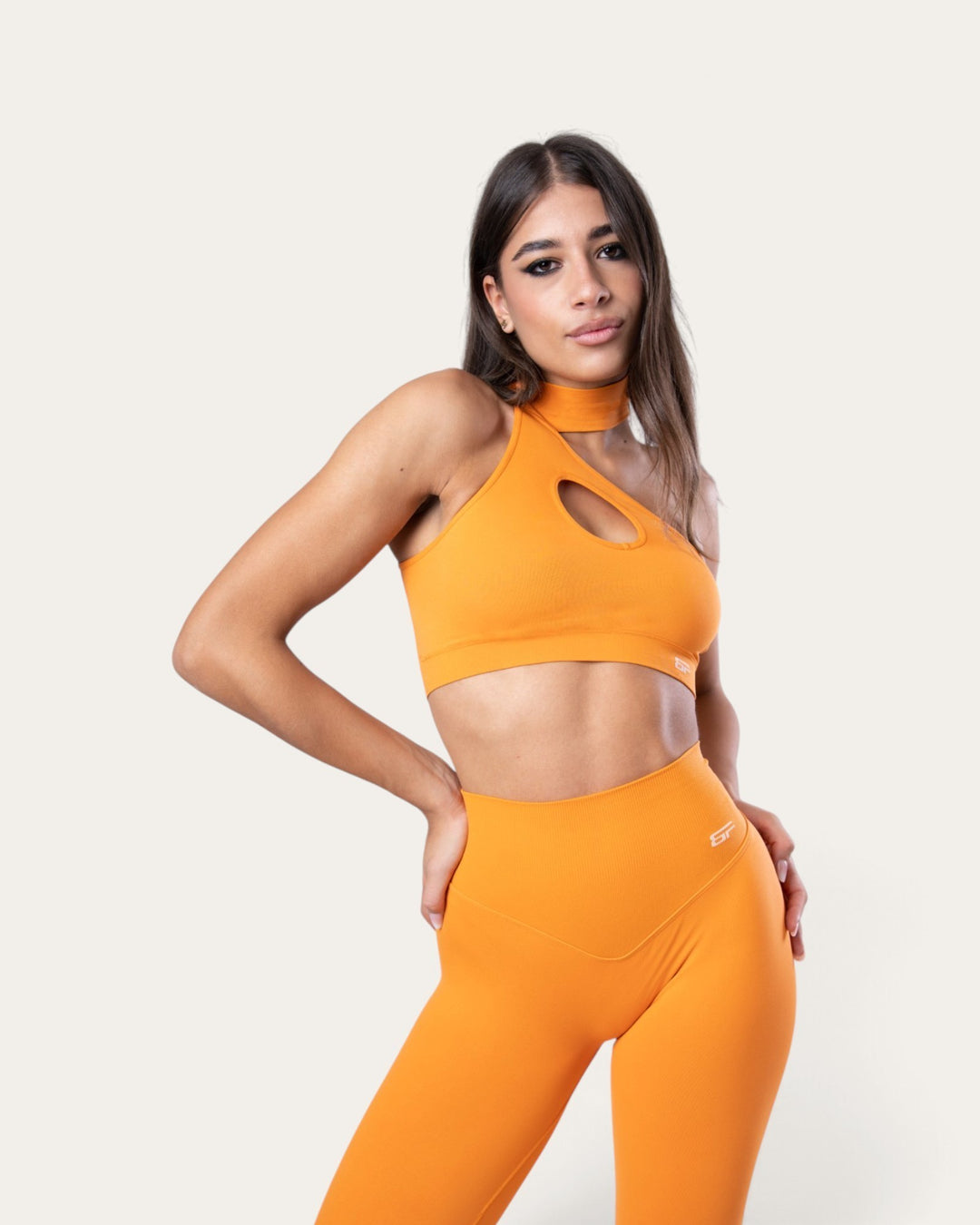 Modella indossa il top sportivo choker seamless arancione Bombafit con dettaglio cut-out e leggings abbinati