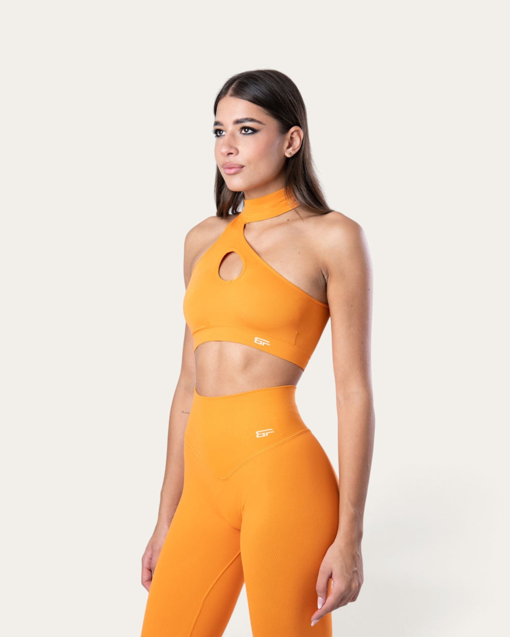 Modella indossa il top sportivo Bombafit Regina delle Zucche, modello choker seamless arancione con apertura frontale