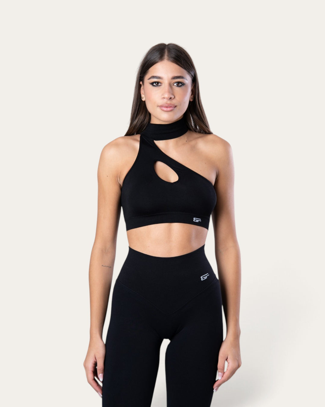 Modella indossa il top sportivo Bombafit Choker Seamless nero con design monospalla e dettaglio cut-out sul petto