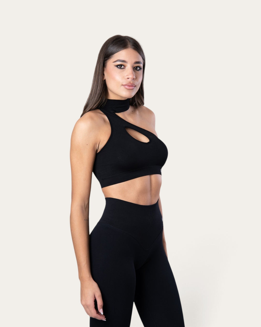 Modella indossa il top sportivo Bombafit Choker Seamless nero con design monospalla e dettaglio cut-out sul petto