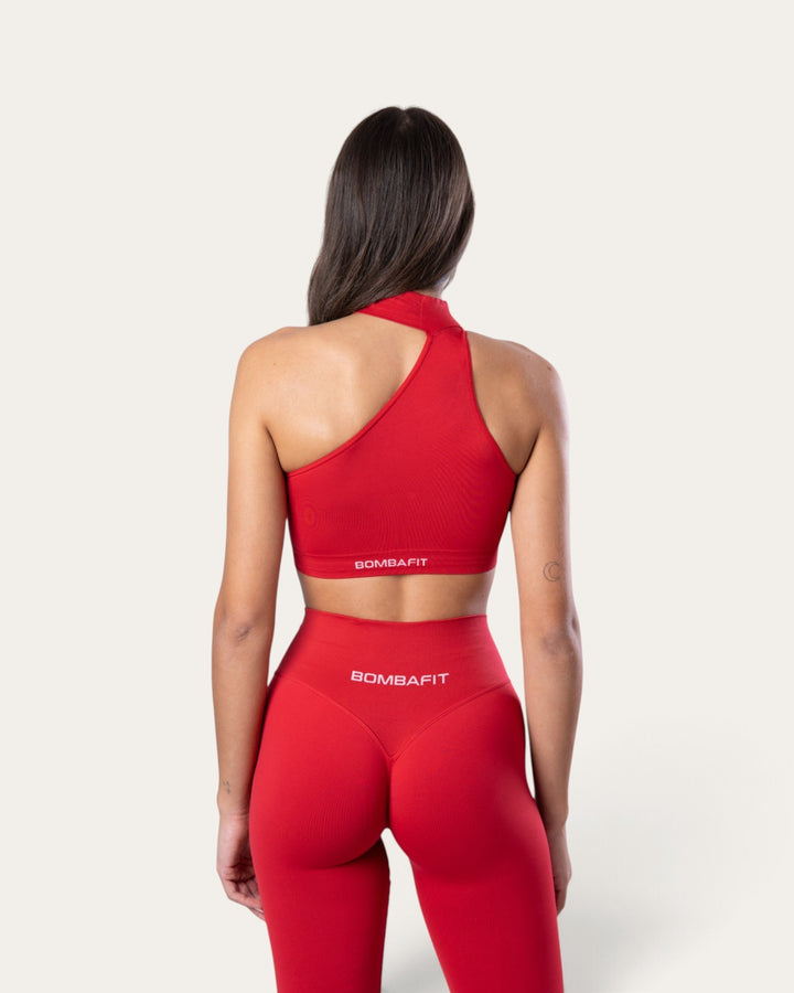 Vista posteriore di una modella che indossa il top sportivo choker seamless rosso sangue di Bombafit