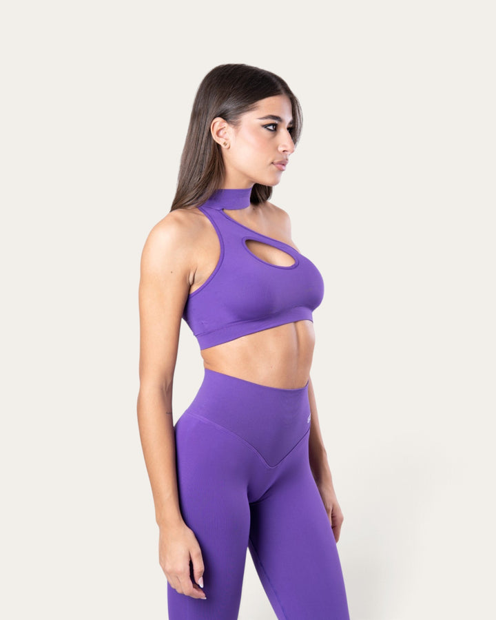 Modella indossa il top sportivo choker seamless viola di Bombafit con design a spalla singola e cut-out frontale