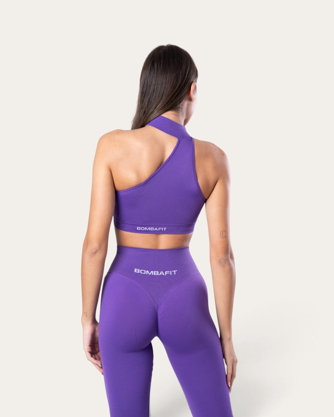 Modella indossa il top sportivo choker seamless viola Bombafit con leggings coordinati, vista posteriore