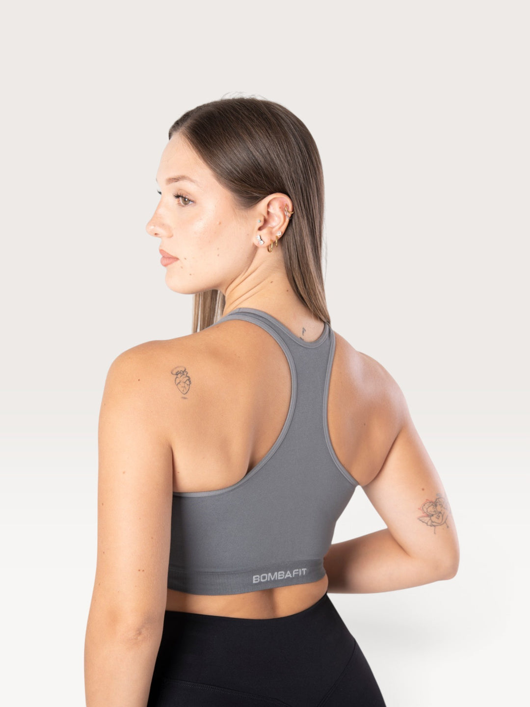 Modella indossa top sportivo Bombafit Go Seamless color grafite con design a vogatore e logo riflettente