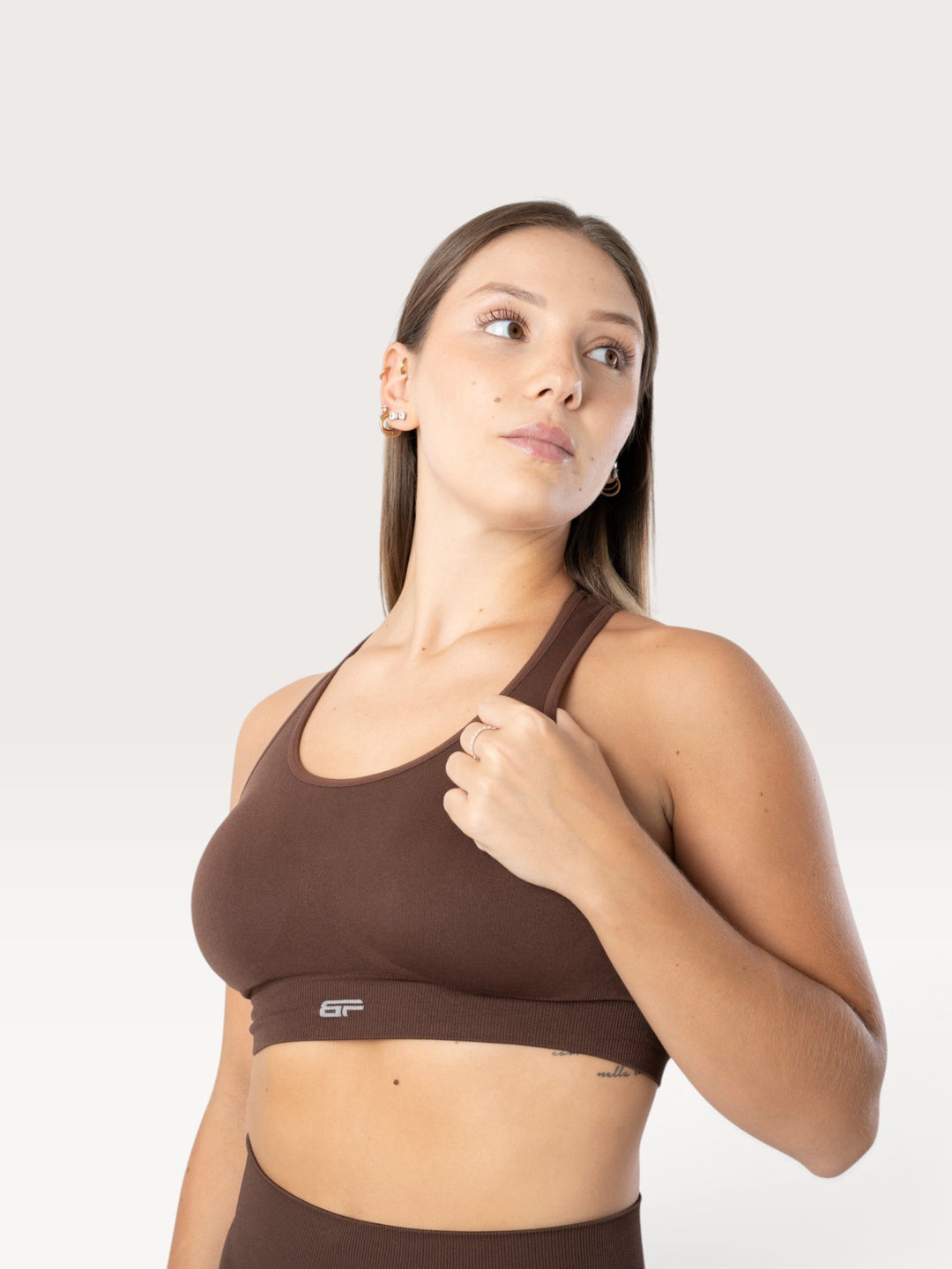 Modella indossa un top sportivo Bombafit marrone senza cuciture con scollo rotondo e logo frontale