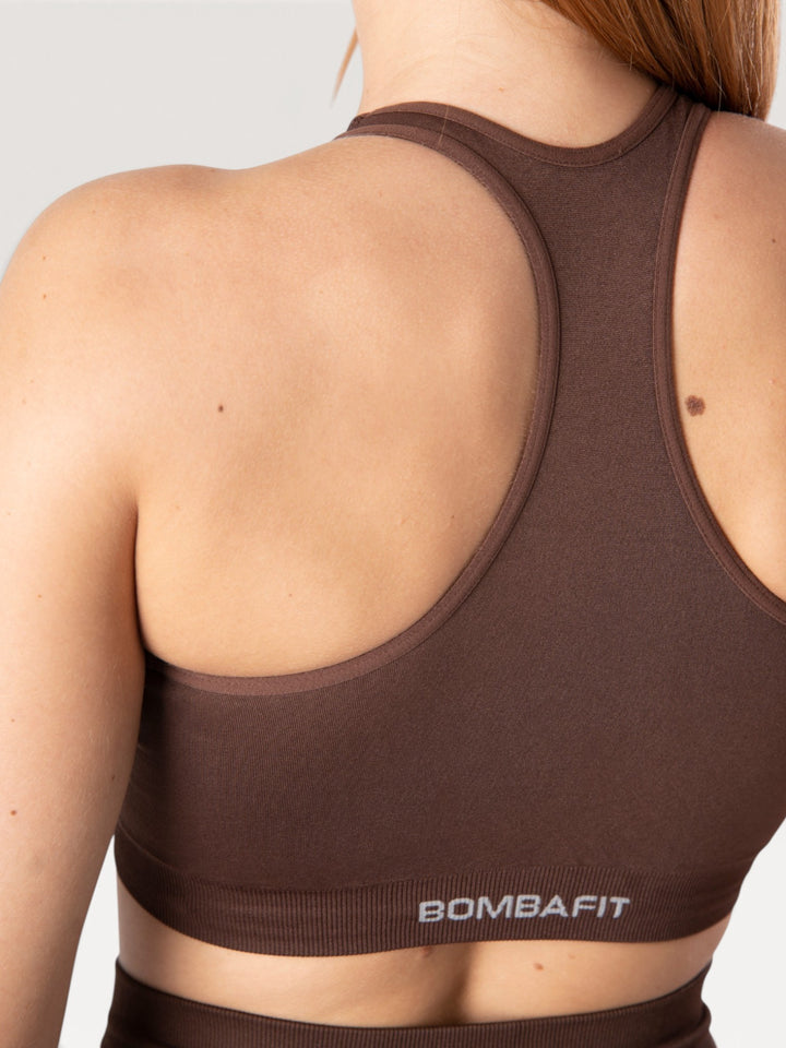 Dettaglio posteriore del top sportivo Bombafit Go Seamless marrone con design a vogatore e logo riflettente