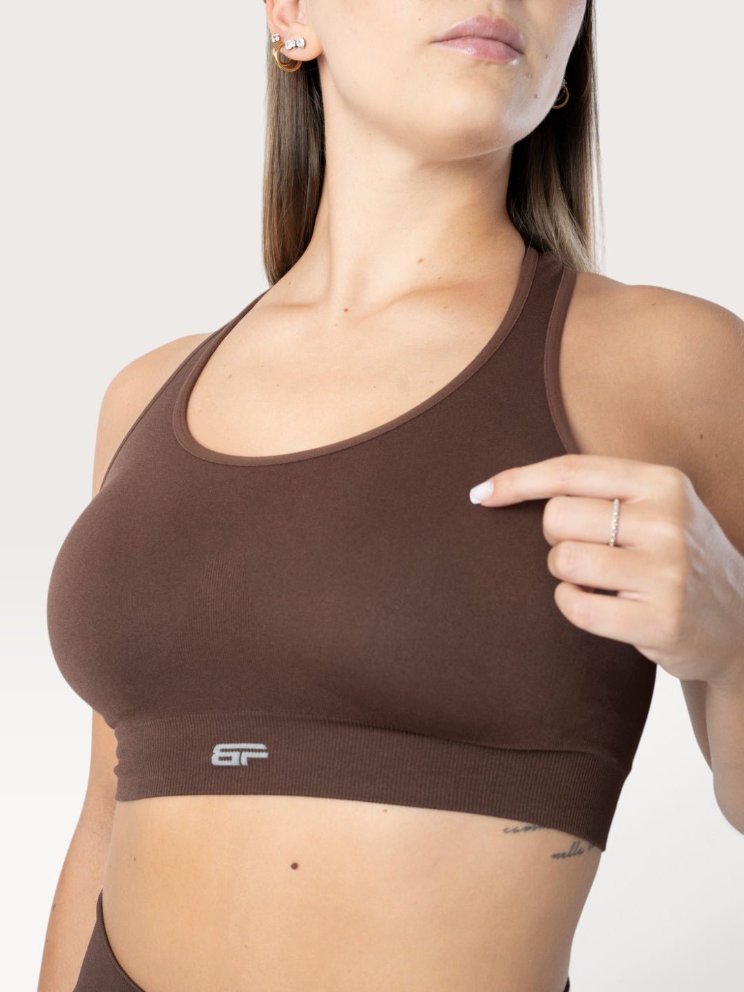 Top sportivo Bombafit marrone senza cuciture con scollo rotondo e logo riflettente, indossato da una modella